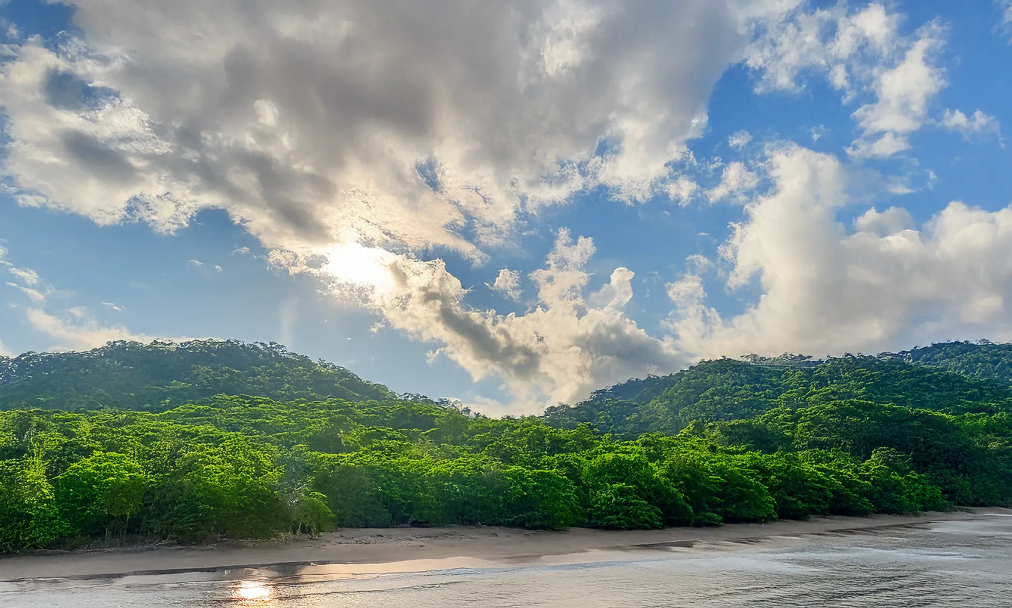Green hills along the coast under a cloudy sky